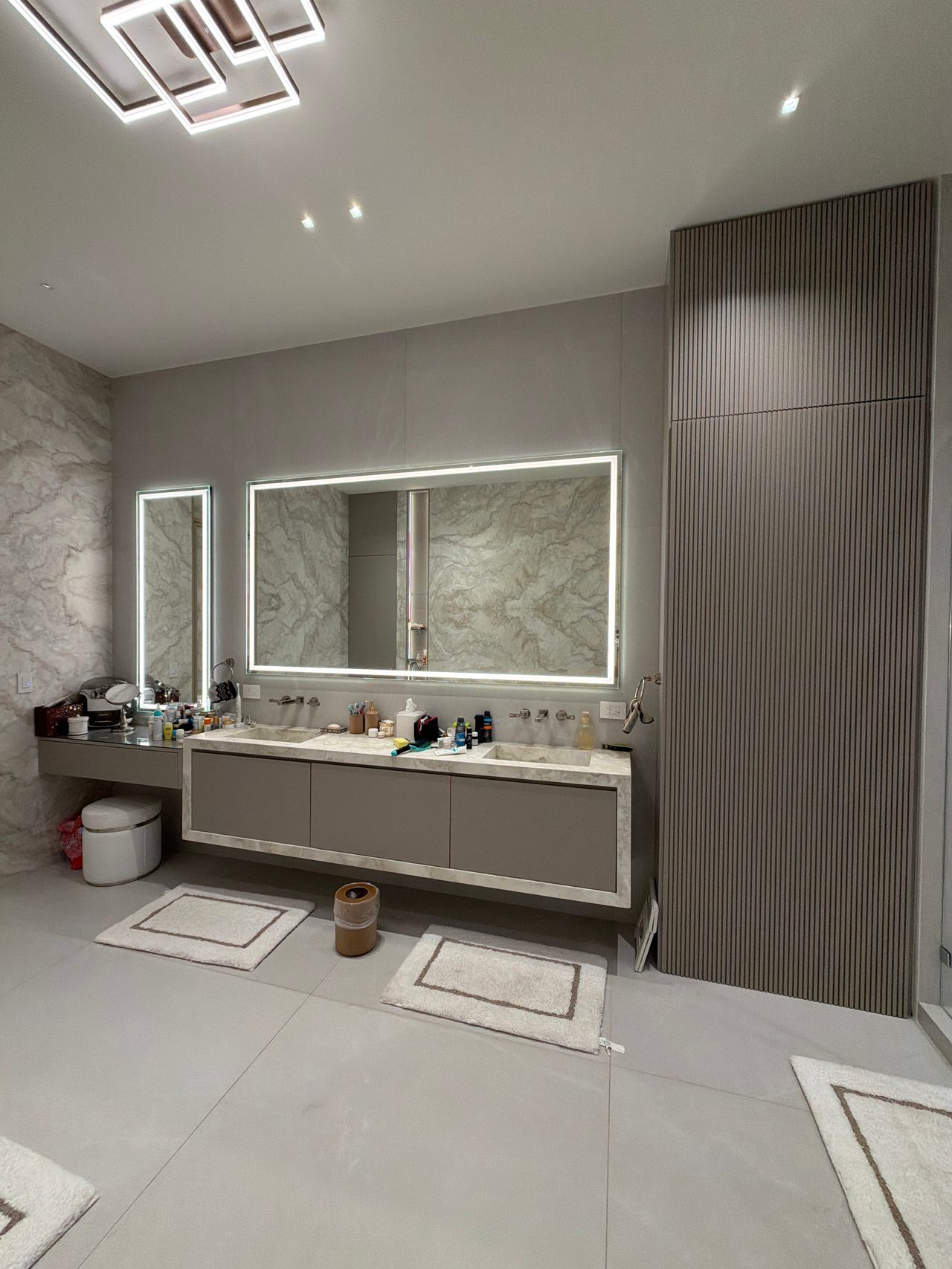 Bathroom with a backlit mirror and vanity with toiletries on the counter