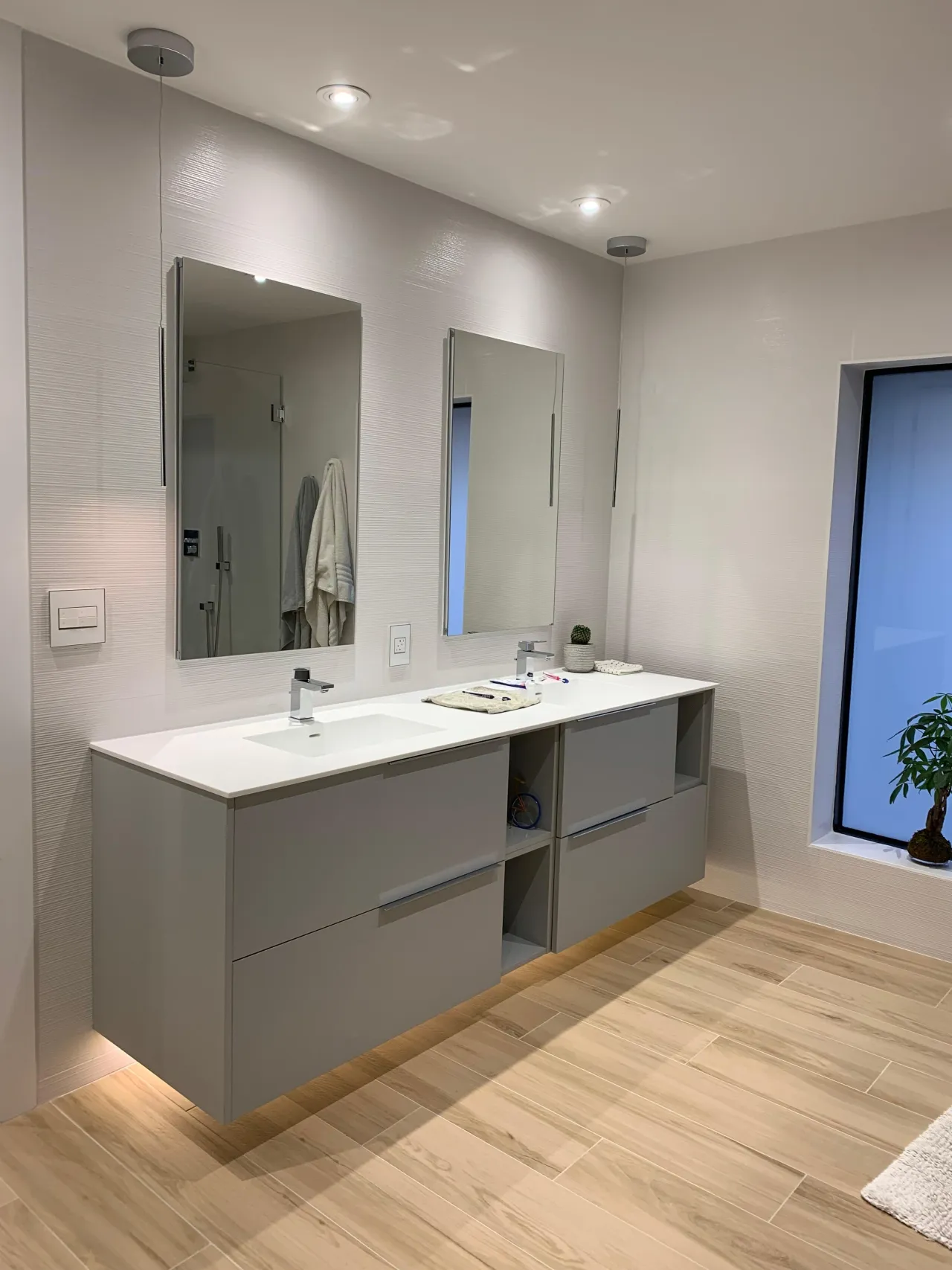 Gray floating double vanity with a white countertop and undermount sink, open cubby shelving at the center, beneath two rectangular mirrors