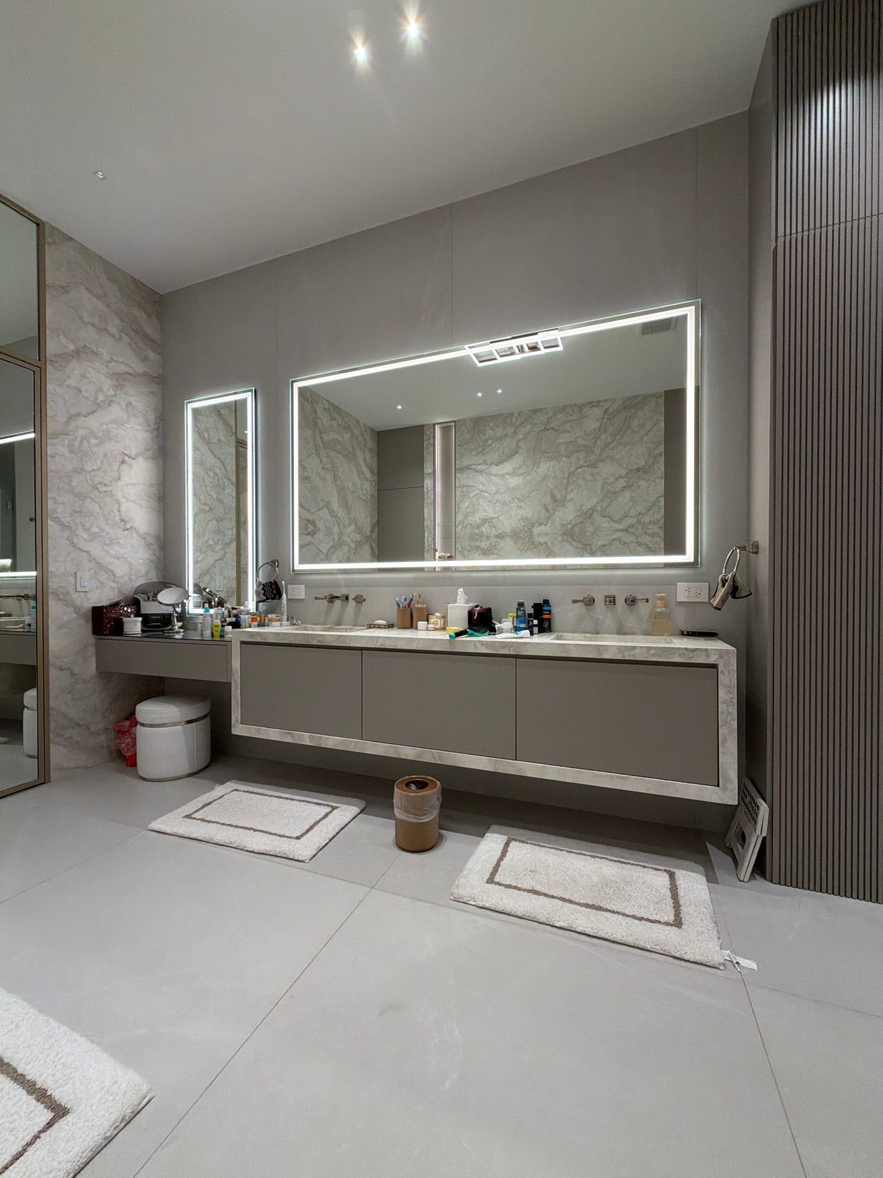 Bathroom vanity with a long stone-look slab top, a taupe cabinet base, and a backlit rectangular LED mirror