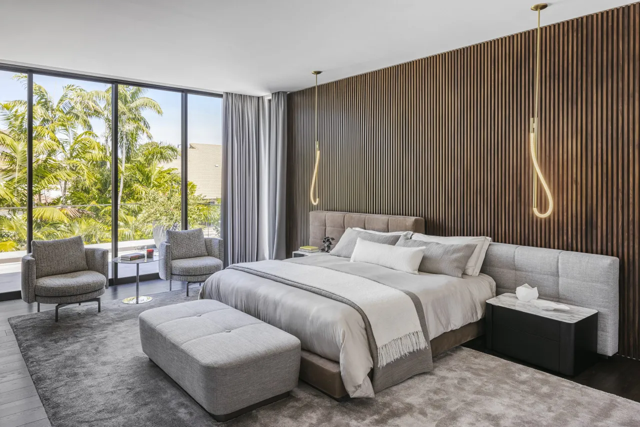 Master bedroom with a dark wood slat accent wall, sculptural pendant lights, and a gray tufted upholstered headboard