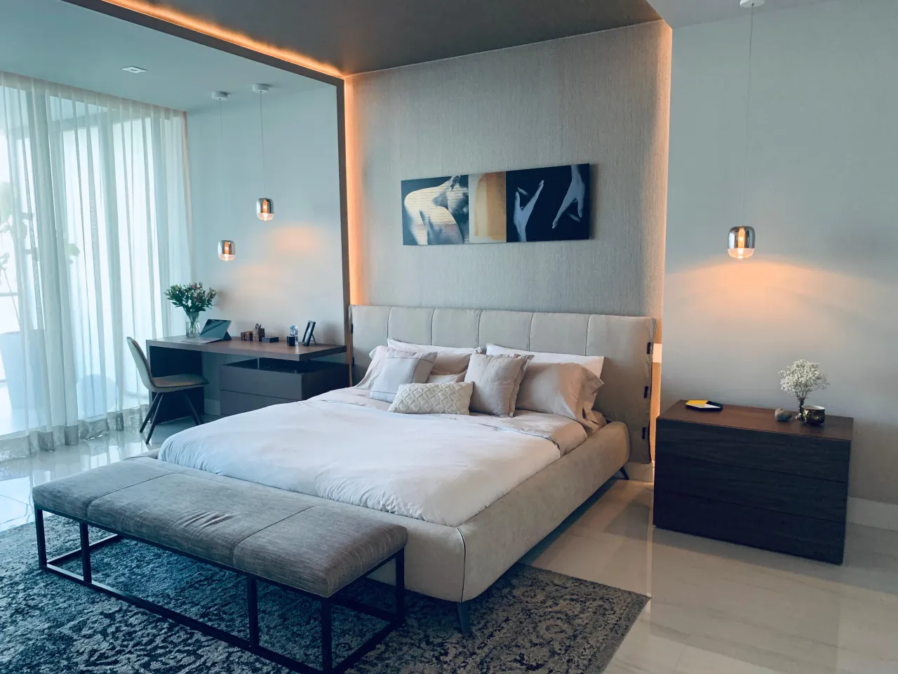 Master bedroom with a large mirror-framed niche around the bed, dark wood nightstands, and hanging pendant lights