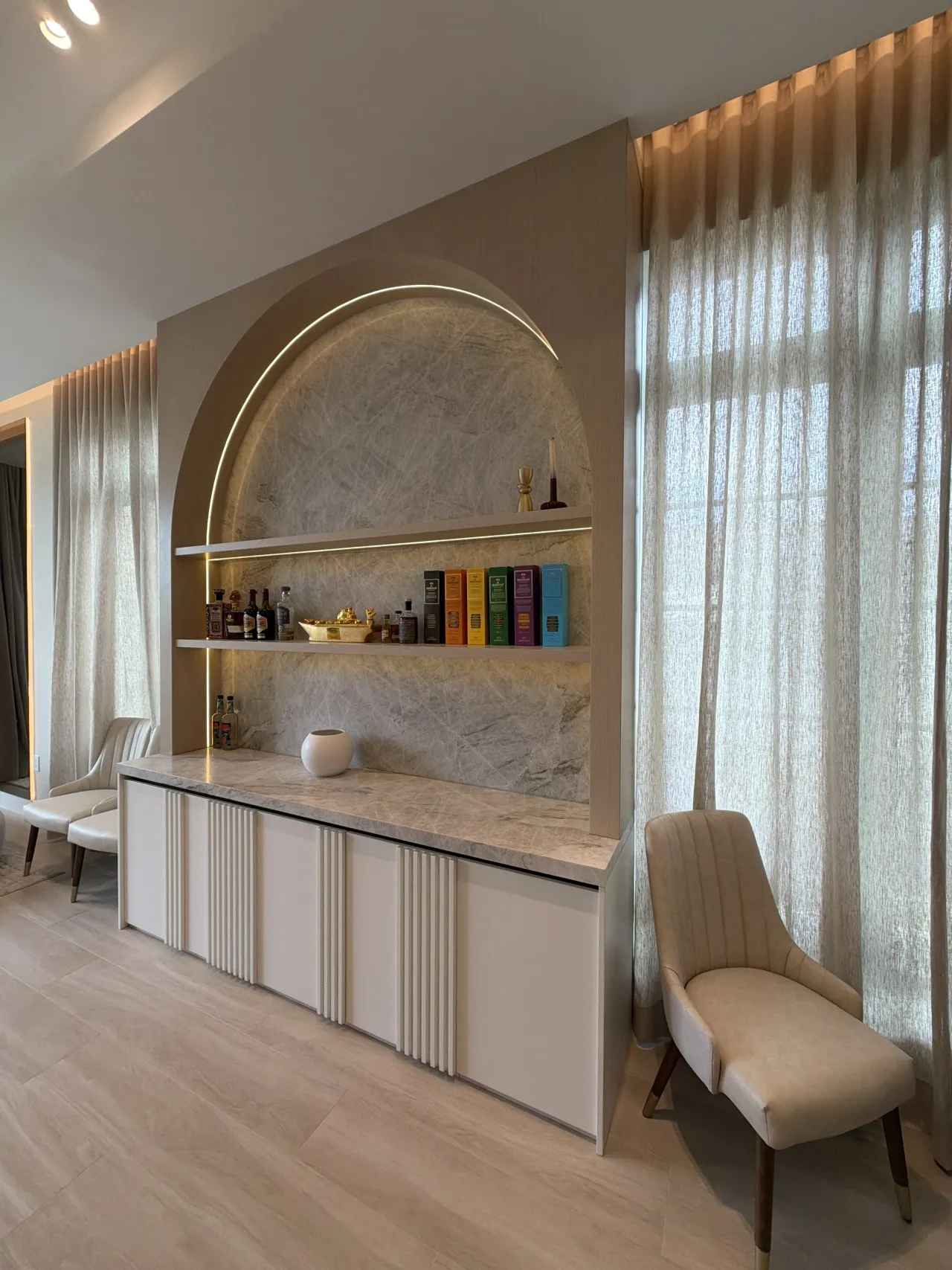Arched taupe bar niche and white fluted credenza from a different angle, sheer curtains nearby