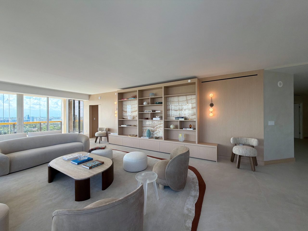 Full-wall custom-stained wood veneer built-in with open shelving, three backlit veined-stone display niches, and a long low credenza base