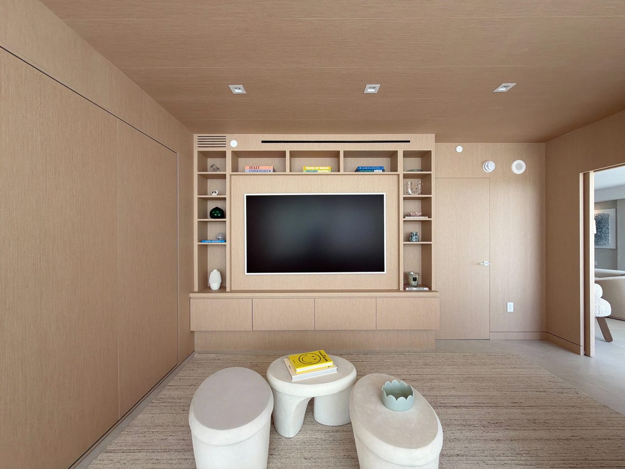 Custom-stained wood veneer media wall centered on a TV room, with a recessed TV, symmetrical open cubbies, and a low floating credenza
