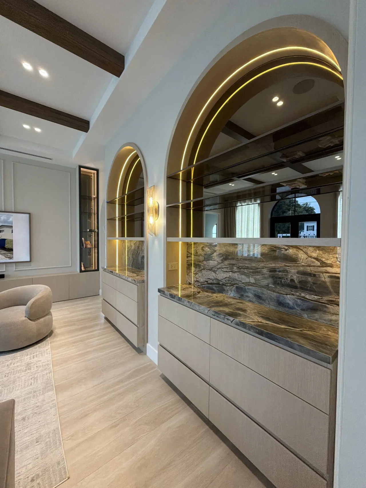 Double arched display niches with veined stone backs, gold-tone LED trim and a wall sconce between them