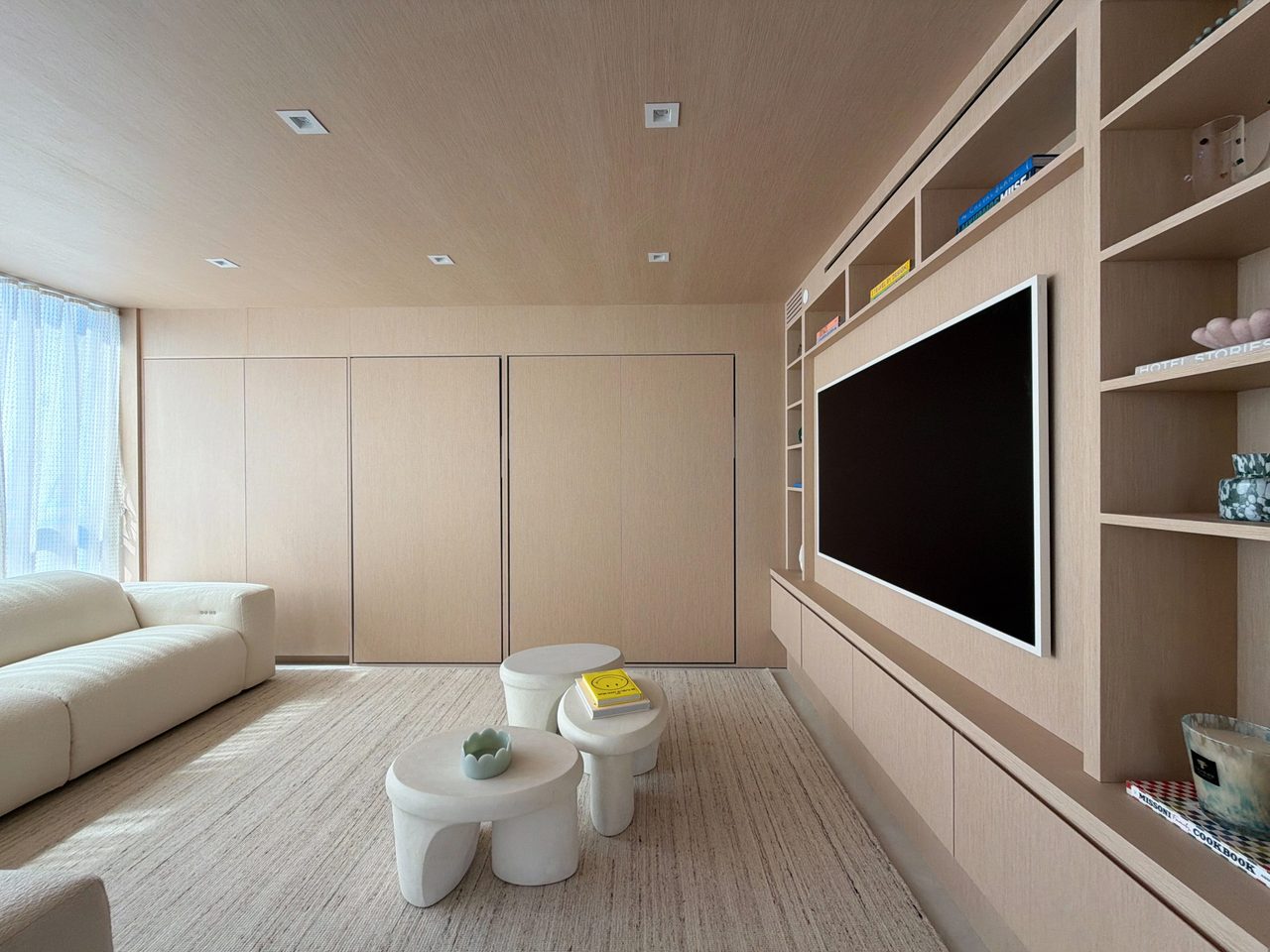 Media room with a custom-stained wood veneer TV built-in, open shelving, a floating drawer base, and flush veneer wall paneling with concealed doors