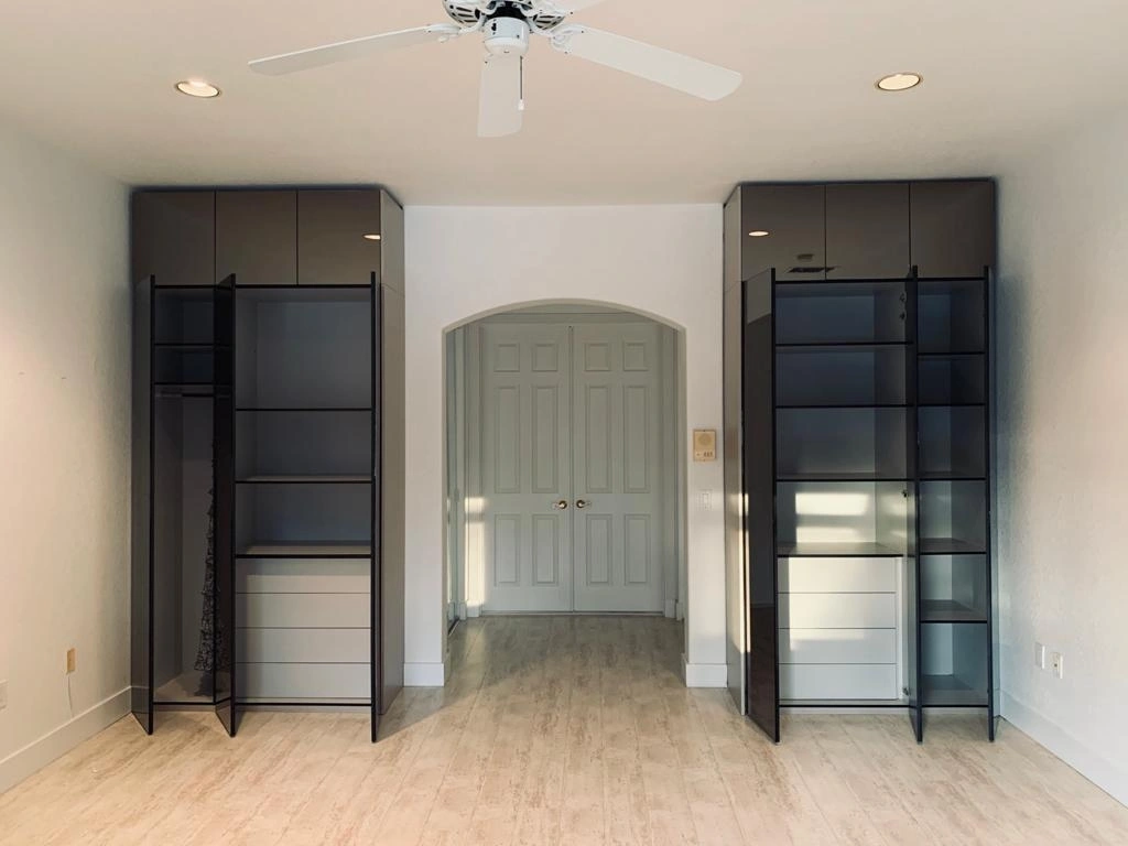 Empty room with two tall dark closet/wardrobe towers flanking an arched double-door entry, ceiling fan overhead