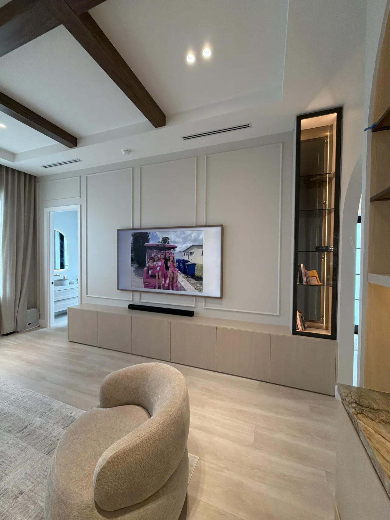 Taupe paneled TV wall room from a different angle showing a hallway and arched doorway