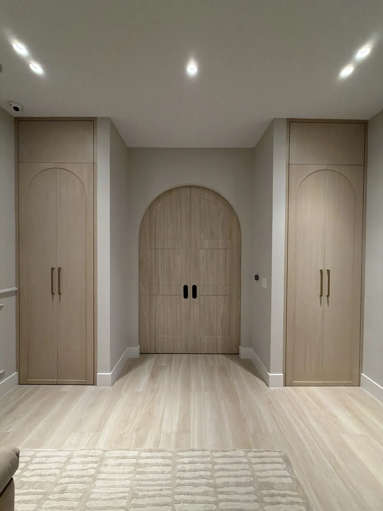 Arched-panel wardrobes around an arched wood-grain melamine double door