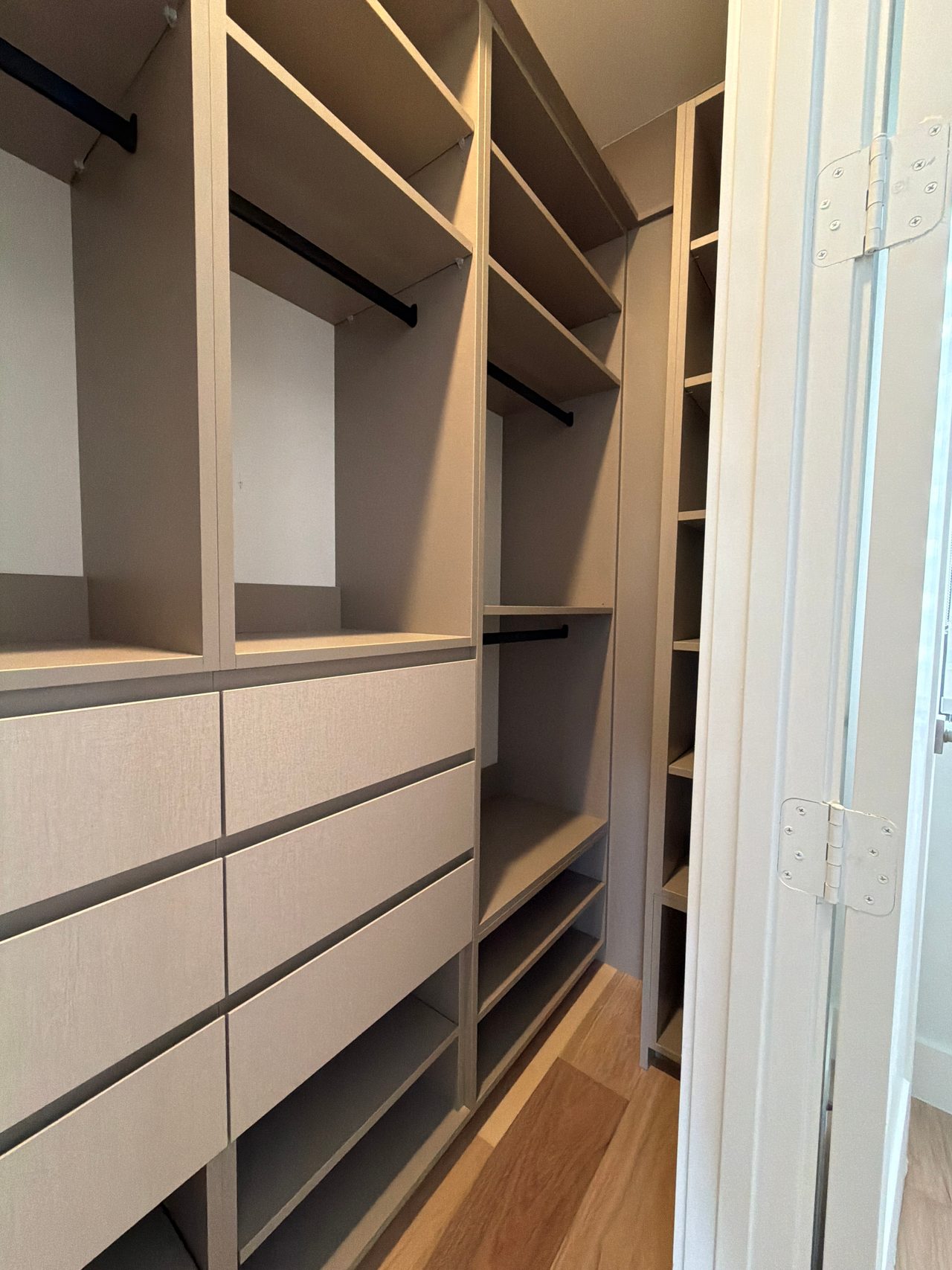 Beige shelving compartments stacked with a black support rod visible