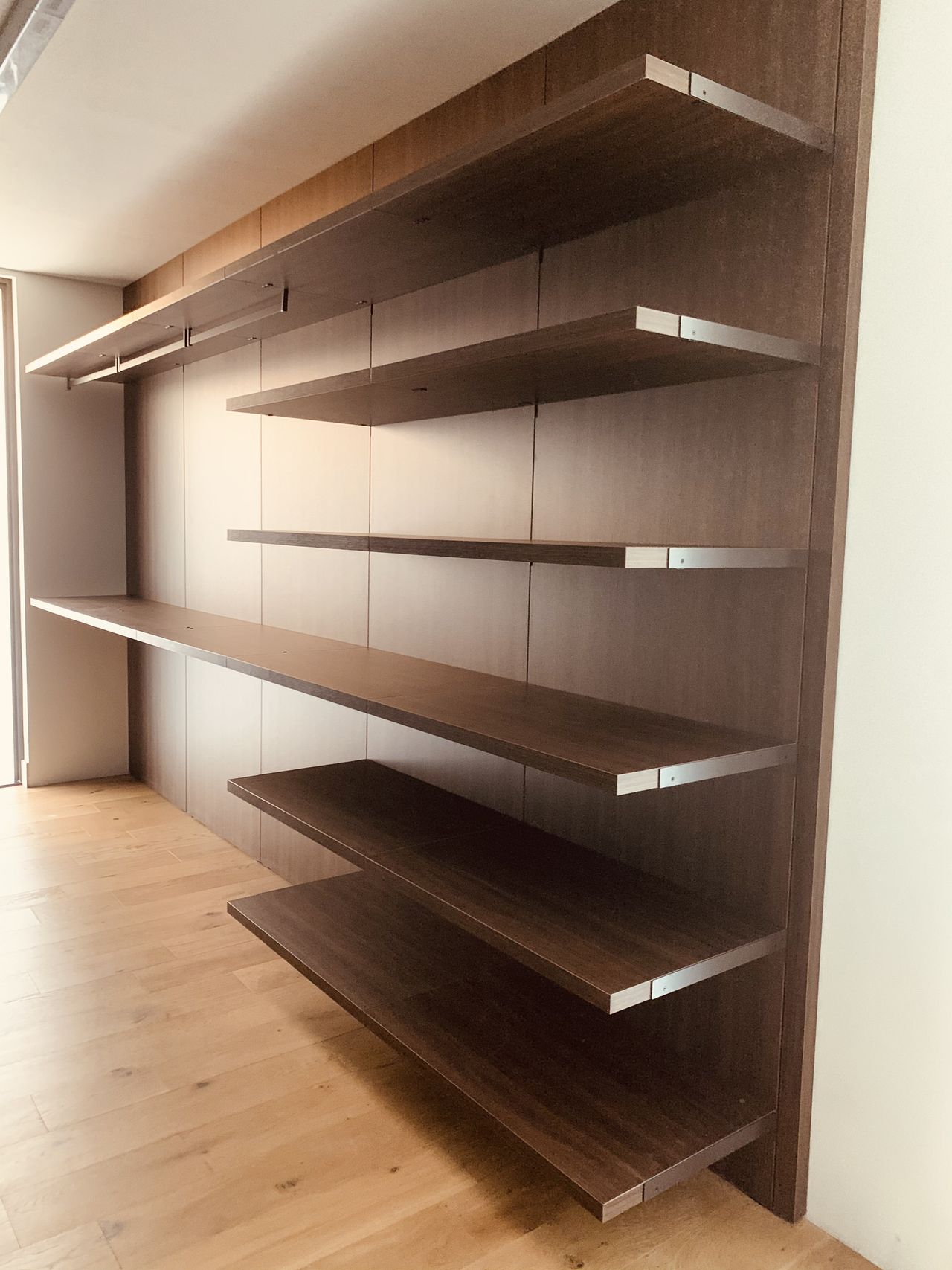 Dark wood floating shelves along a wall, with a light wood plank floor below