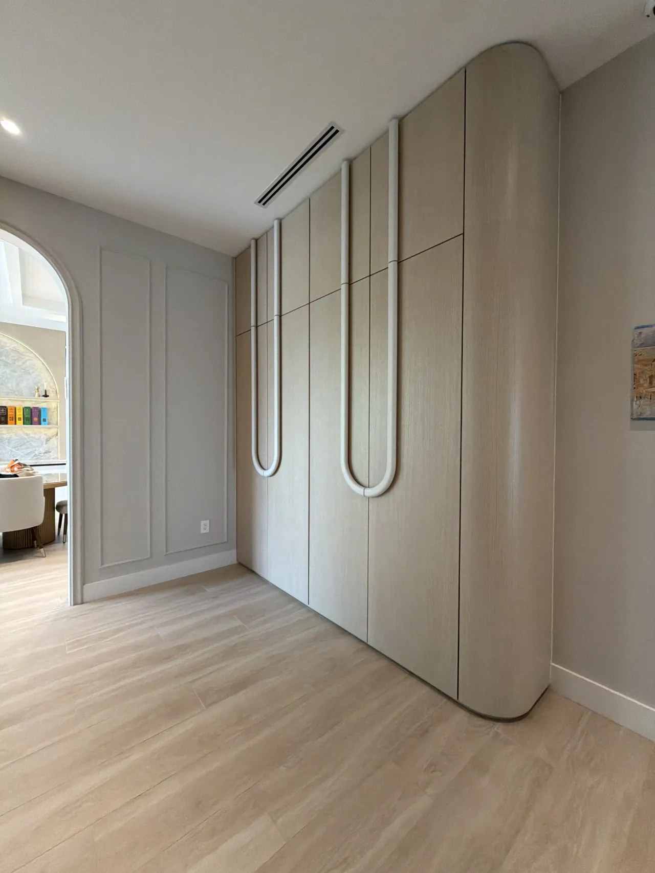 Light wood-grain melamine wardrobe with a curved end cap where the cabinet meets the wall