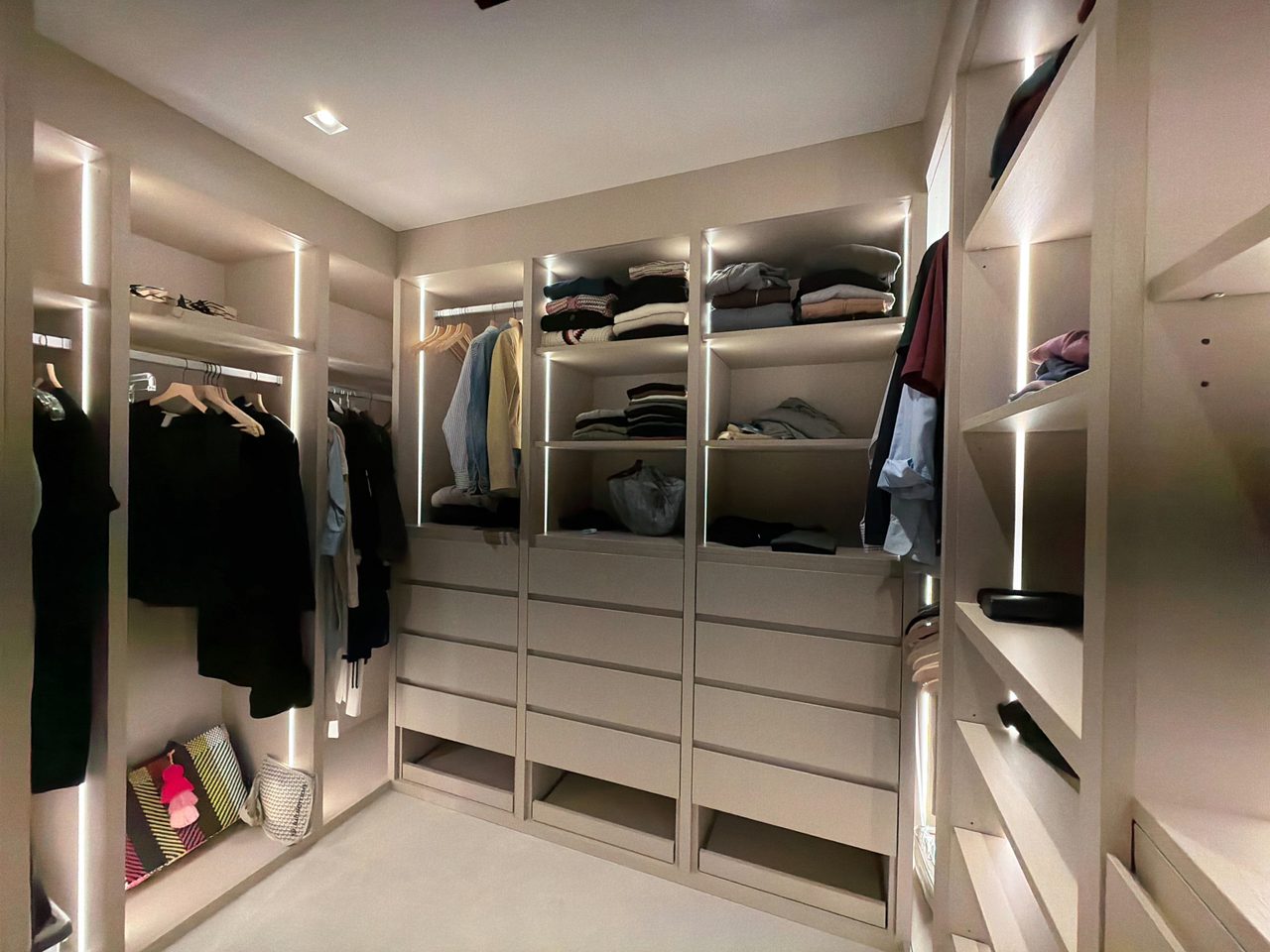 Gray melamine closet with LED-lit open shelving over three drawer towers, hanging rails on the side walls, and open cubbies at the base