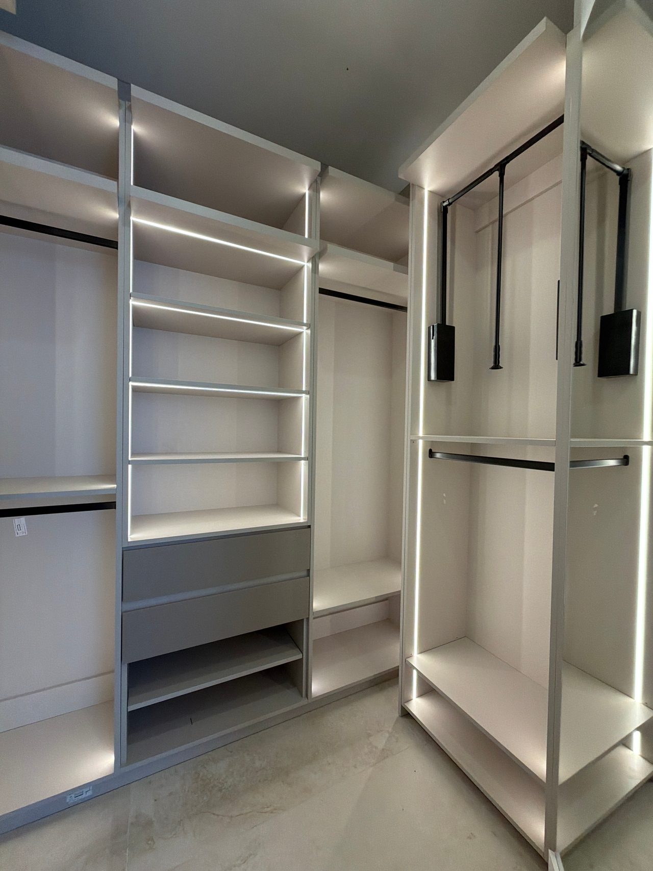 Motorized pull-down closet rods with garment holders above open shelving compartments