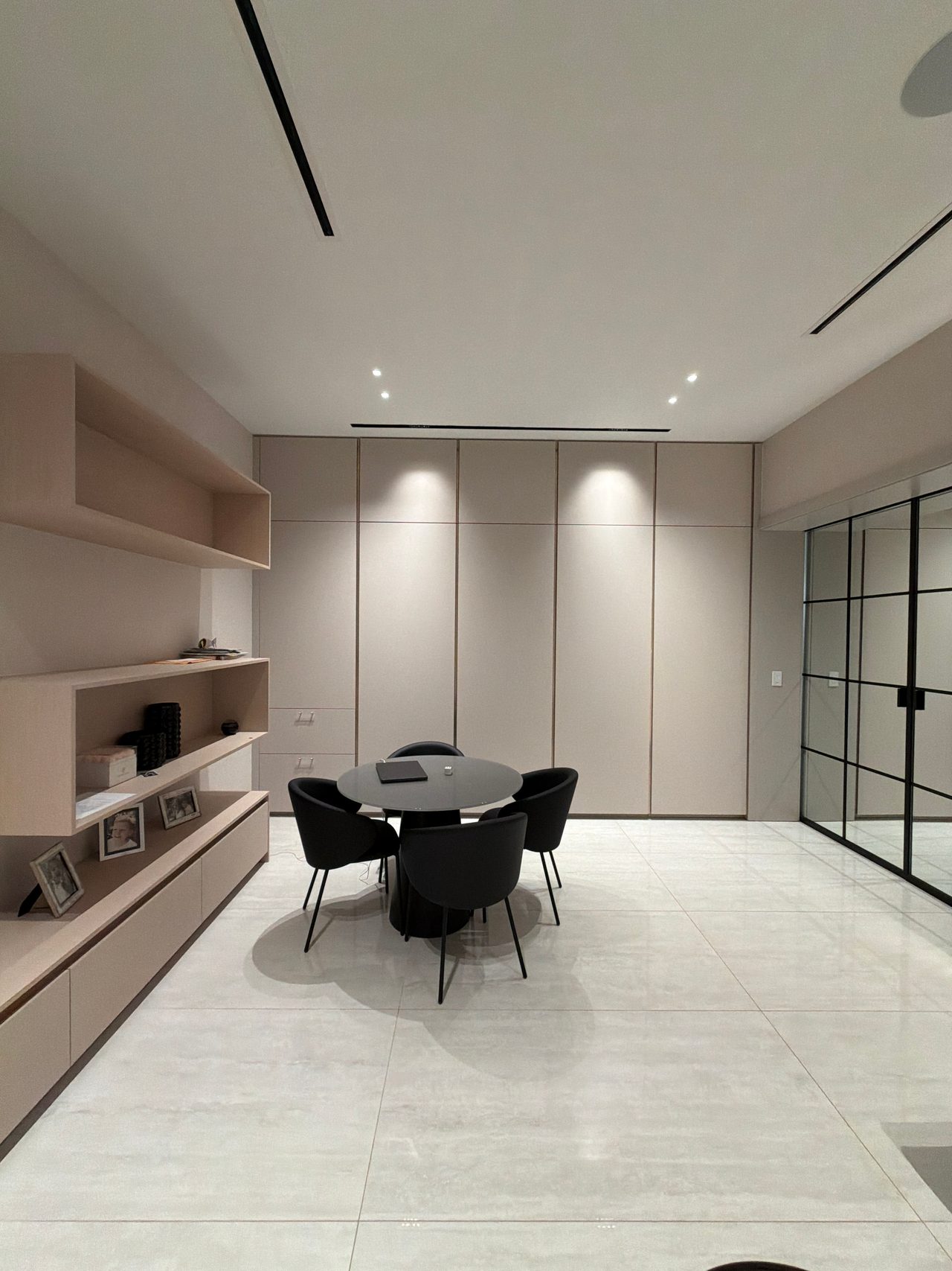 Paneled taupe wall in a dining/office area with a round table and black chairs