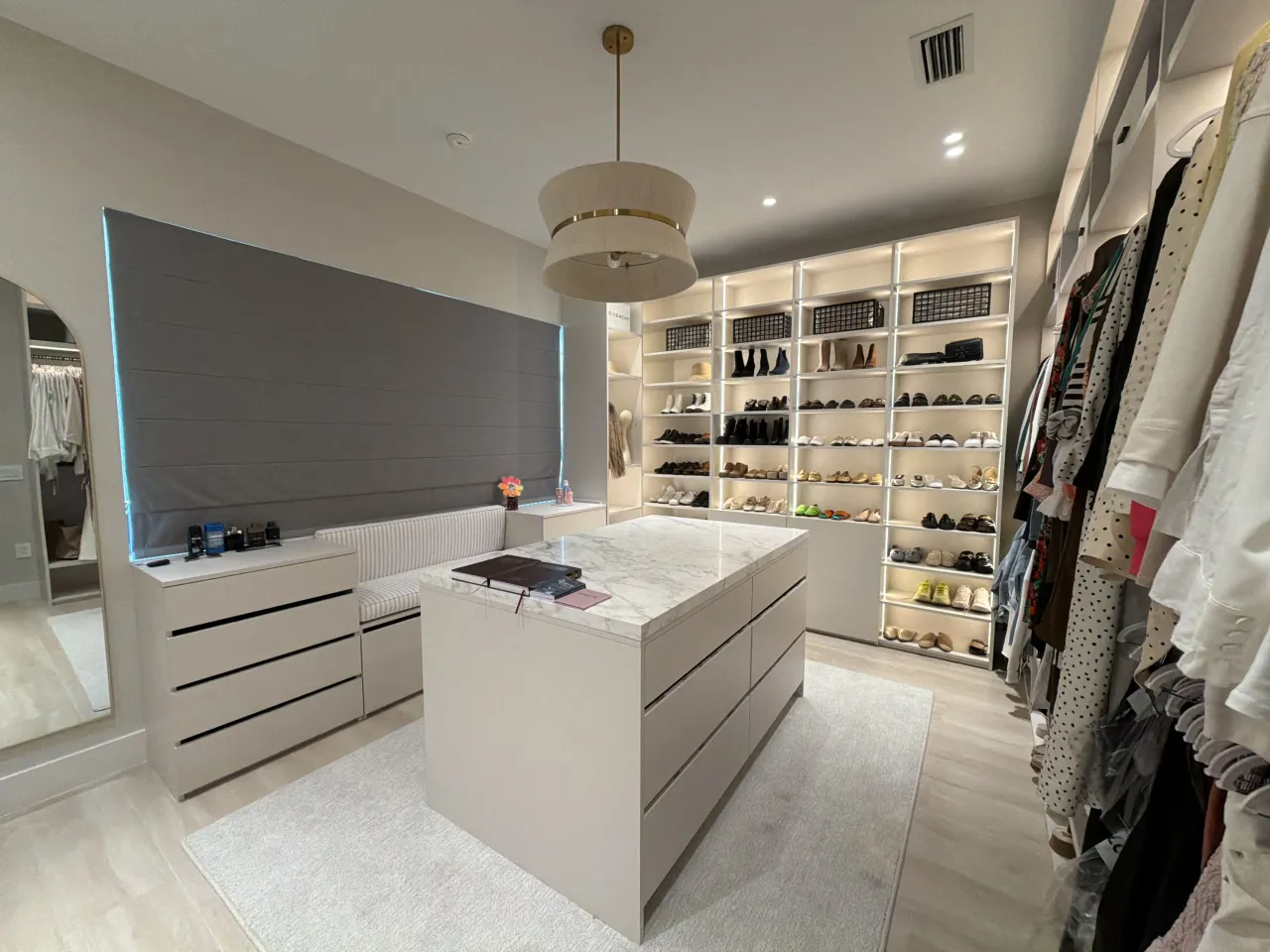 Walk-in closet with a stone island, a drawer dresser, and shoe/handbag shelving with LED lighting