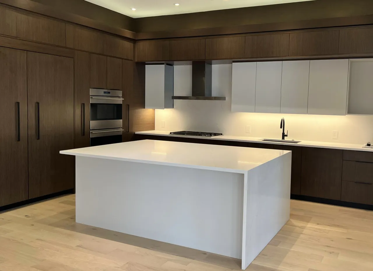 Dark wood kitchen with a large white stone island, a stainless double wall oven, and light hardwood flooring