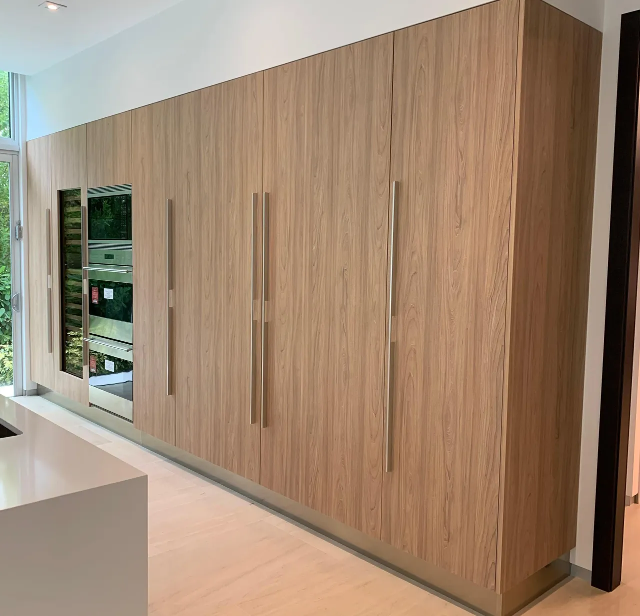 Light wood floor-to-ceiling pantry wall with long brushed-nickel bar pulls
