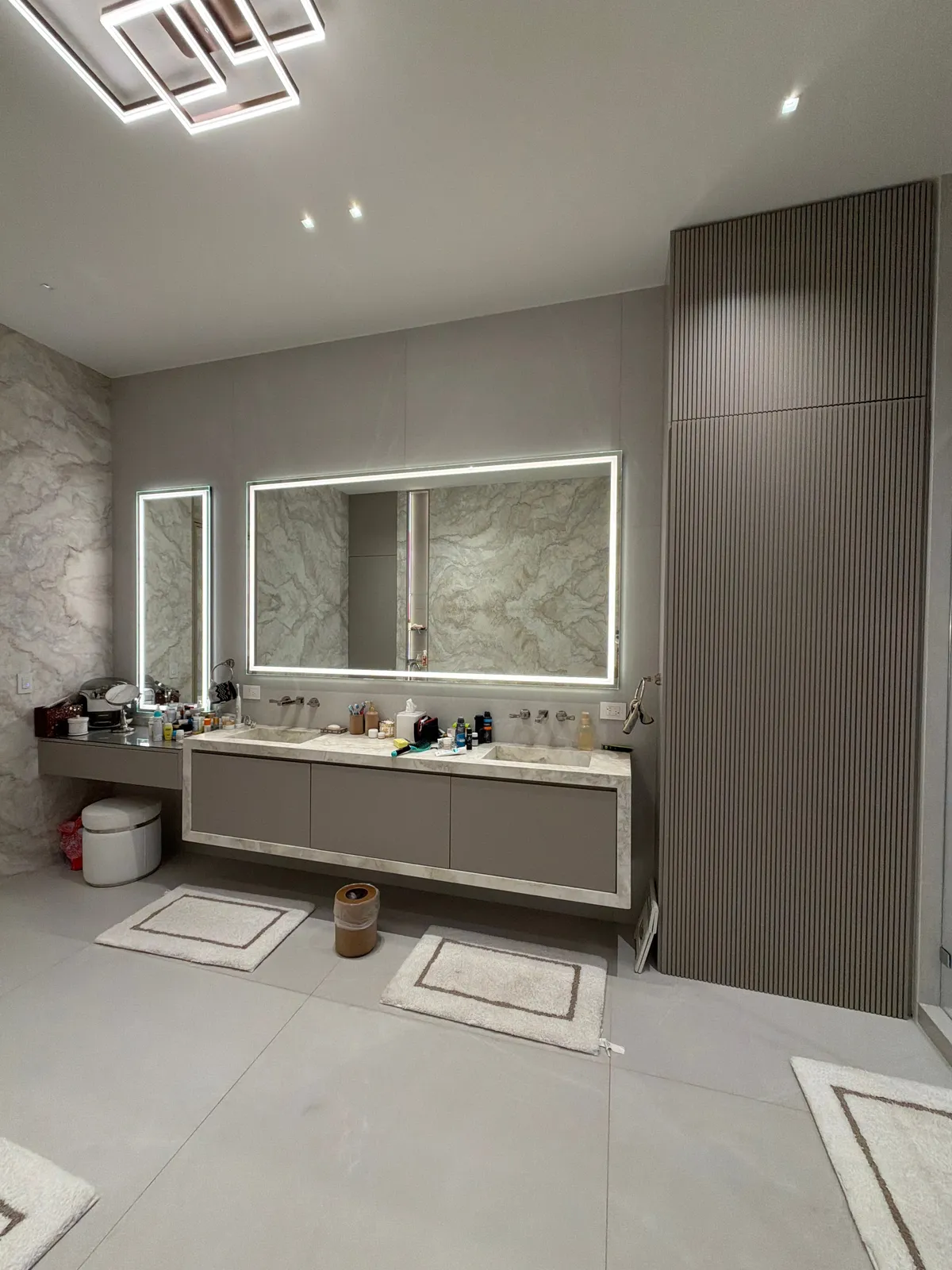 Bathroom with a backlit mirror and vanity with toiletries on the counter