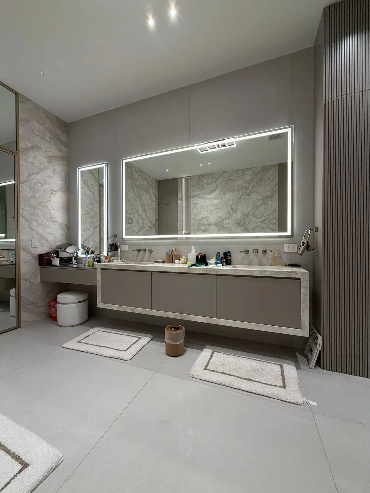 Bathroom vanity with a long stone-look slab top, a taupe cabinet base, and a backlit rectangular LED mirror