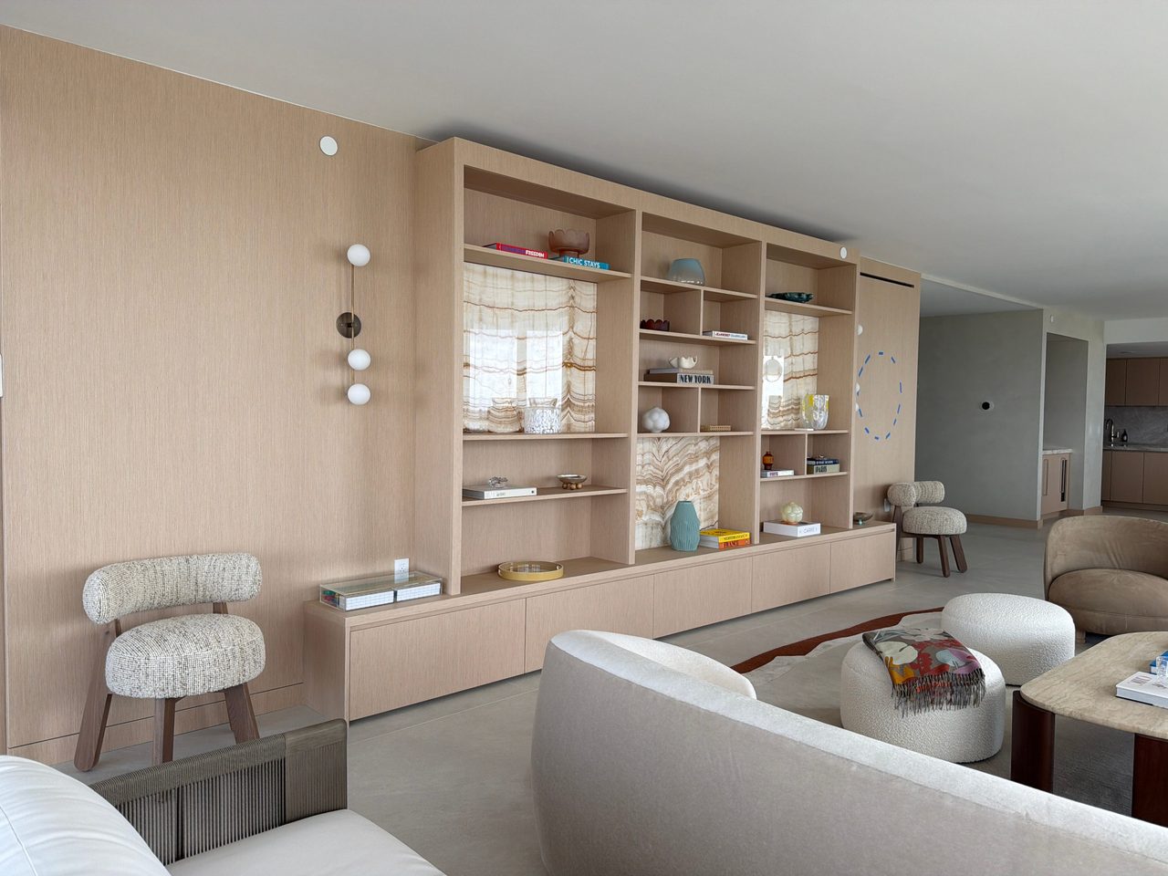 Full-height custom-stained wood veneer wall paneling running into a built-in display unit with backlit stone-look niches and a long floating drawer base