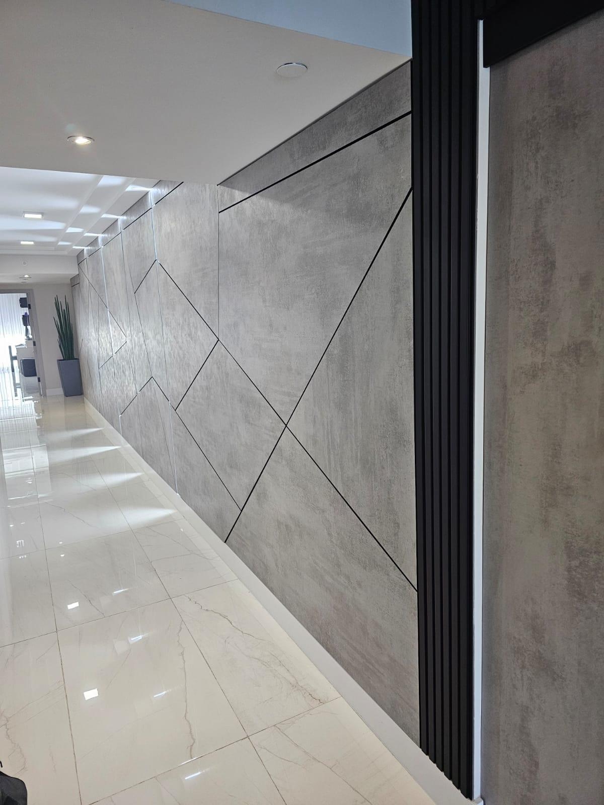 Gray concrete-look wall panels with black inlay lines, a ribbed black vertical trim column at the end of the run, glossy veined tile floor