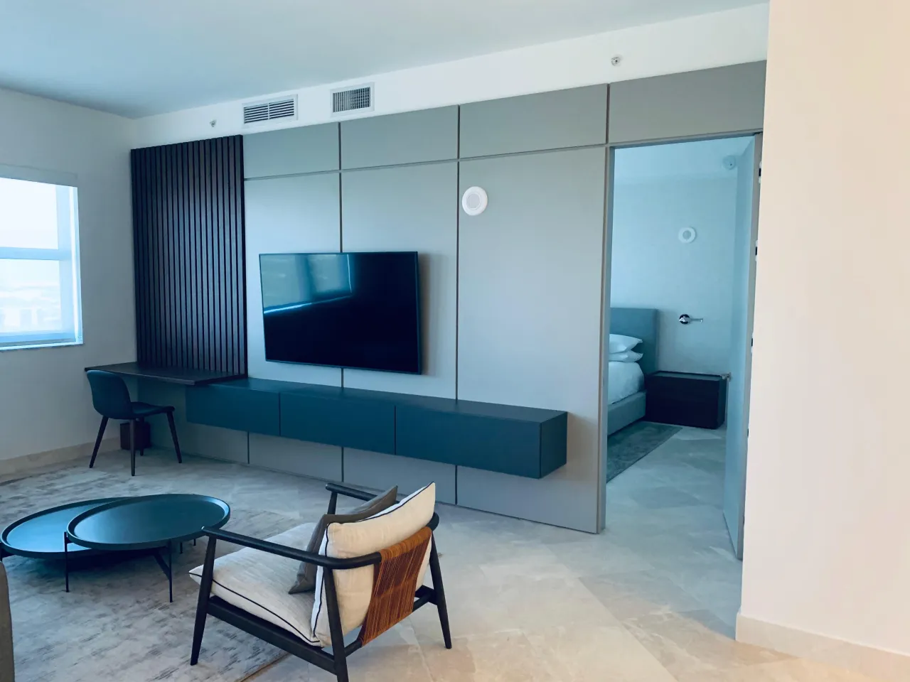 Living room media wall with a narrow dark slat accent panel beside a gray panel section holding a mounted TV over a dark floating console