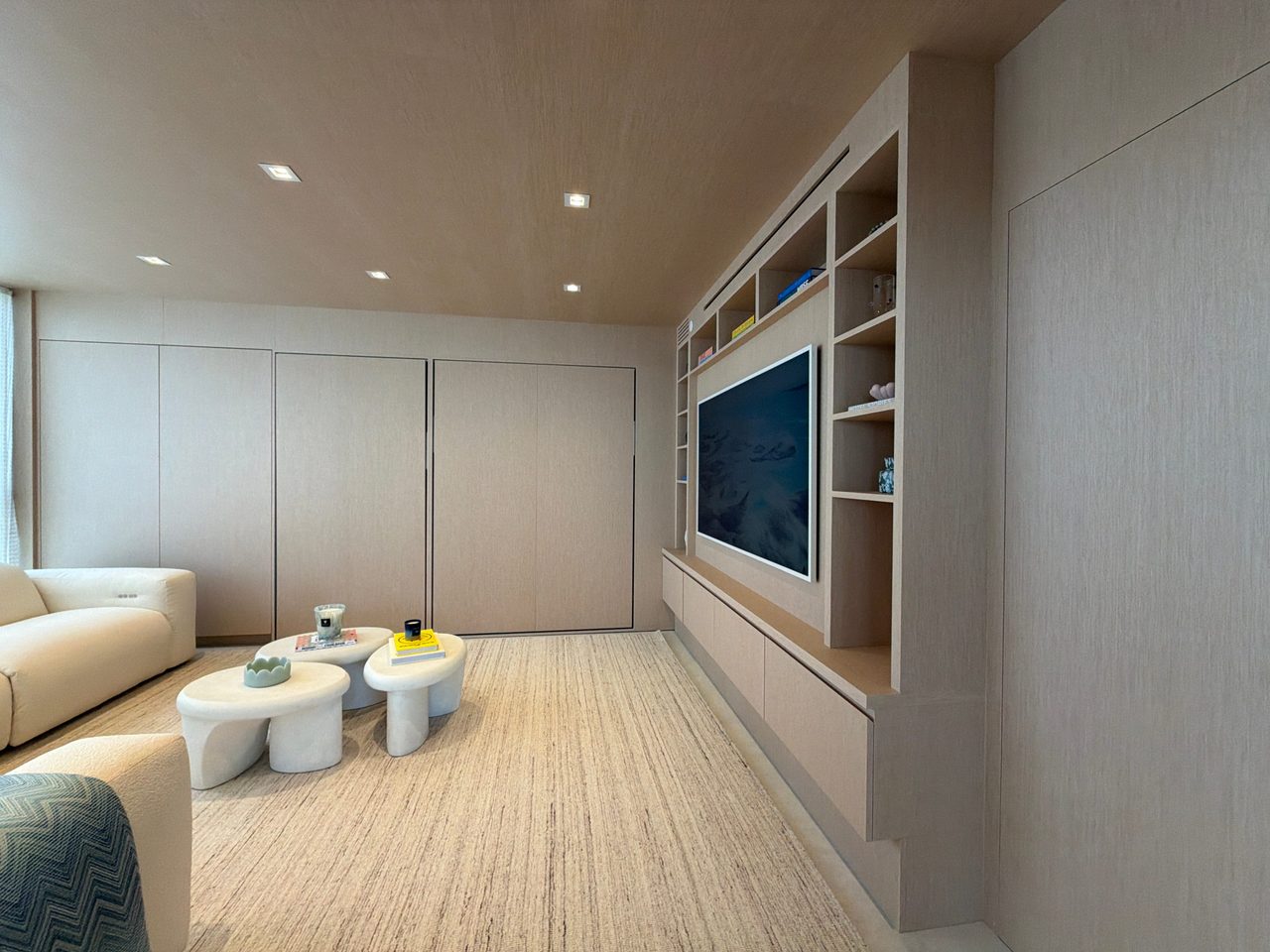 Custom-stained wood veneer room with tall flush panel doors along one wall and a built-in media unit with open shelving over a floating cabinet run