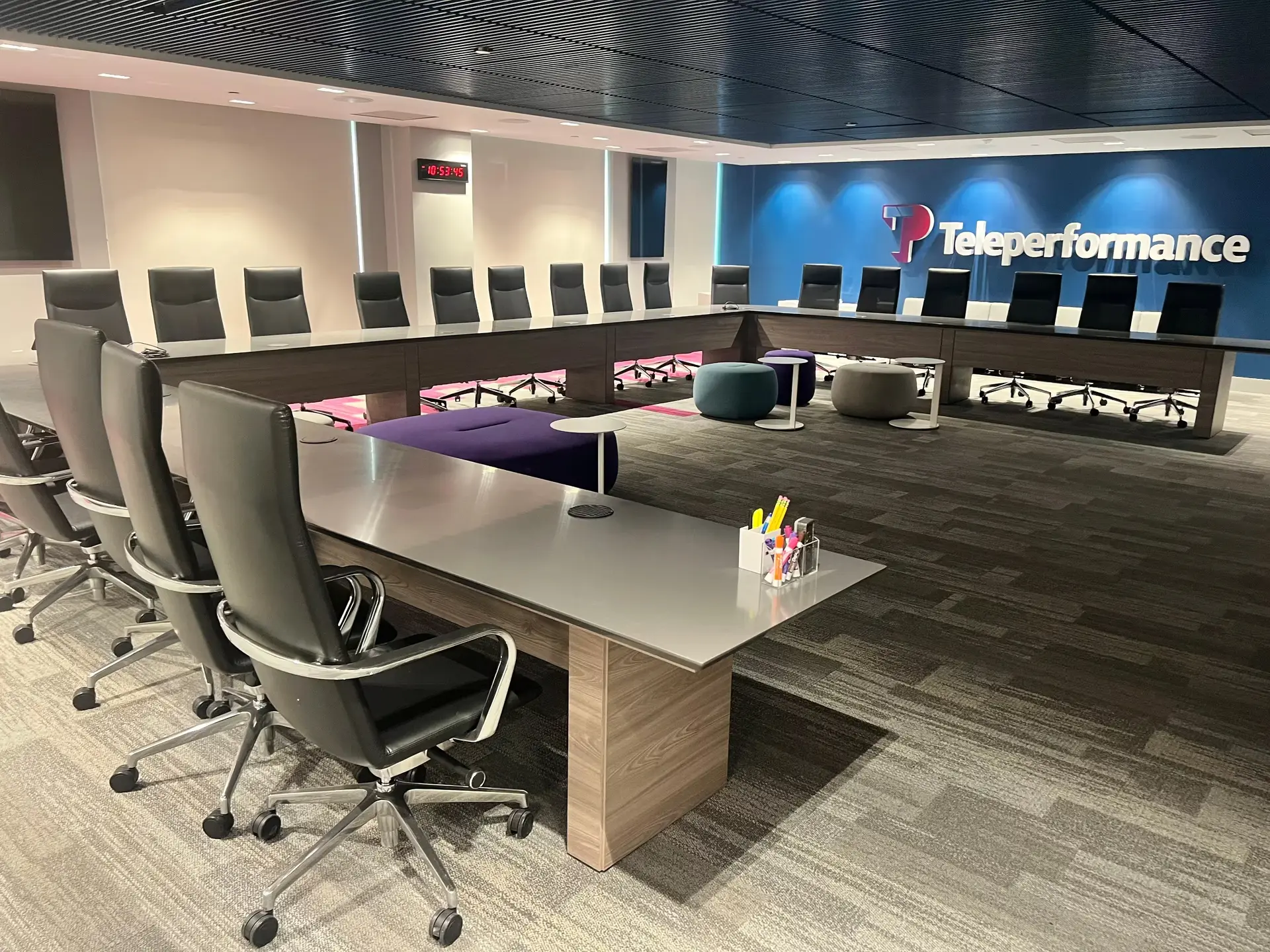 Conference room with a large U-shaped wood-base table configuration and black leather chairs