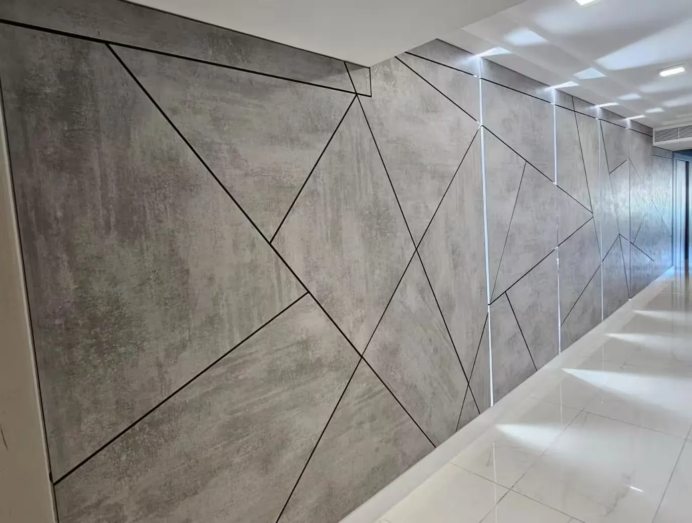 Feature wall of large-format panels with an inlaid geometric pattern of black lines along a hallway